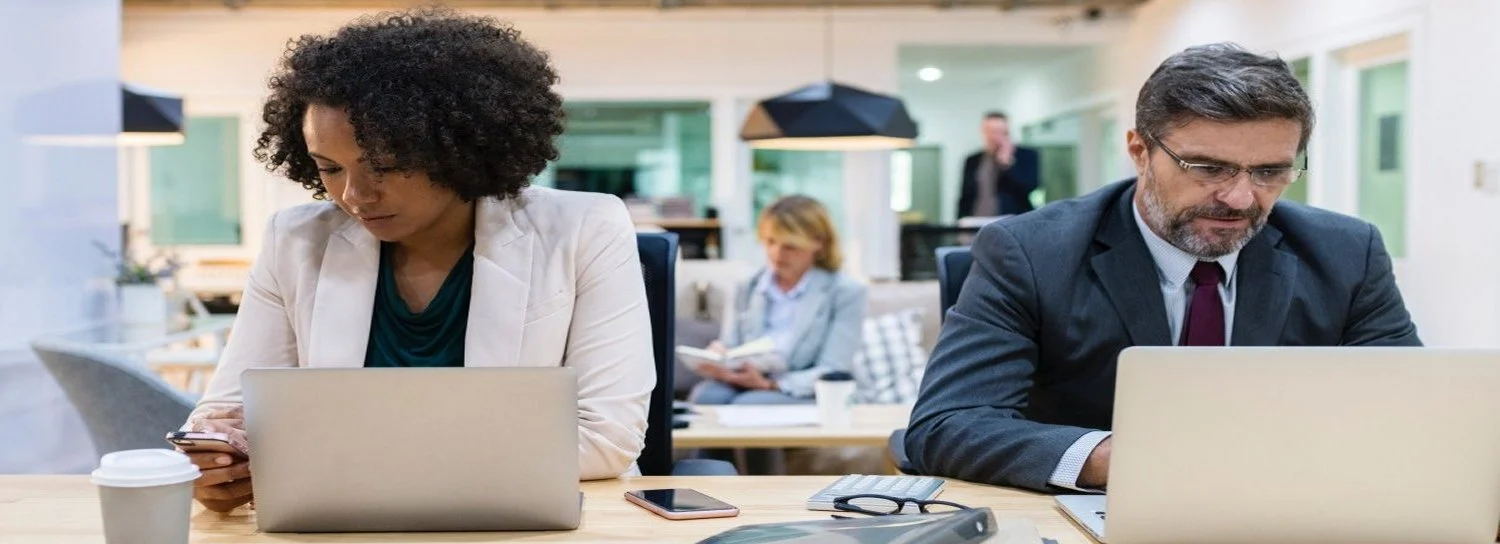 Colleagues working on laptops in a shared office