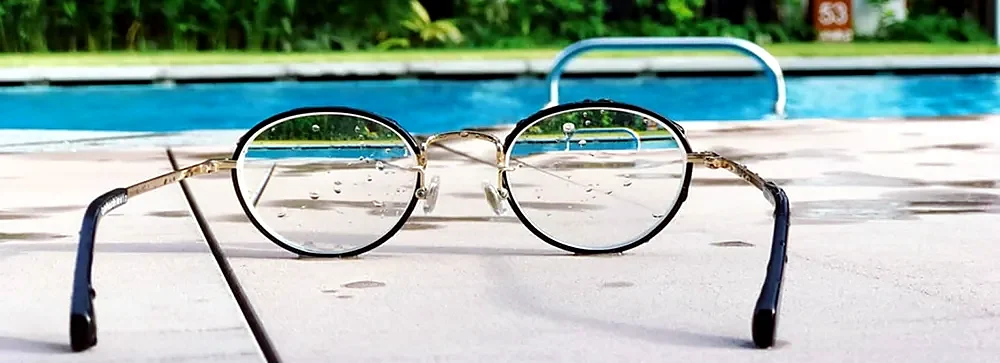 A pair of glasses on paving beside a pool